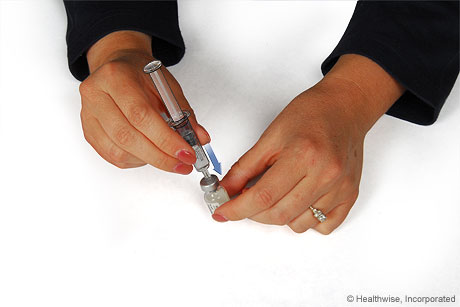 Inserting the needle into the medicine bottle